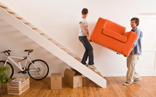 Dos personas bajando un sillón por una escalera con el servicio de ayudante